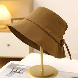 Detailed texture of cotton bucket hat featuring a metal tag and elegant rear bow tie