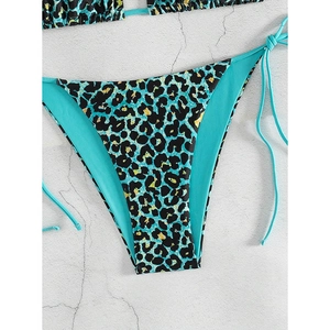 Detail of teal leopard print bikini bottom with side ties on a grey stone background