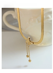 Detail of gold butterfly pendant with frosted texture and hanging fringe balls