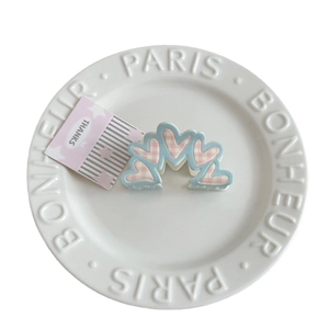 Floral plaid hair claw clips with bow patterns on a decorative white display plate