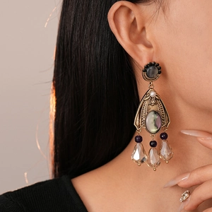 Close-up of vintage gold earrings with colorful crystals and pearls on a female model