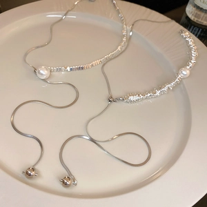 Detailed view of silver snake chain with white pearl and bolo style sliding geometric beads