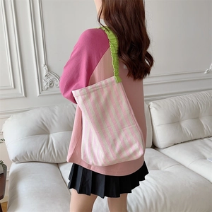 Canvas tote bag with pink and white stripes and green ruffled strap in life scene