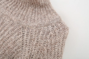 Macro detail of the light brown knit sweater texture and ribbed turtleneck collar