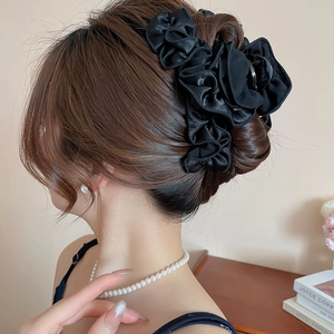 Elegant black pleated fabric flower hair claw clip styled on a low bun hair look