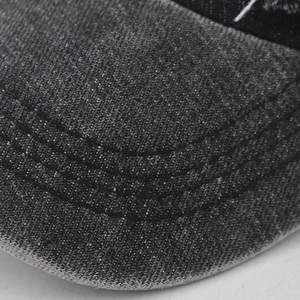 Detail of three parallel stitches on washed black denim baseball cap brim for texture
