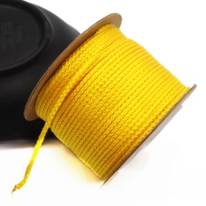 Close-up of 1.5mm yellow cotton cord neatly wound on a spool for DIY jewelry making