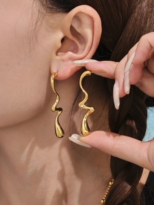 Gros plan détaillé de longues boucles d'oreilles dorées ondulées en acier inoxydable