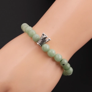 Detail of 8mm faceted green beads bracelet with silver crown charm on wrist
