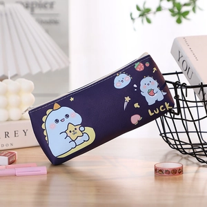 Close-up of a dark blue cartoon dinosaur pencil case with Luck text on a wooden desk