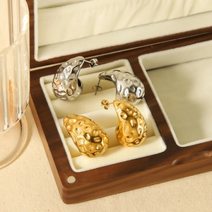Lava texture teardrop earrings in gold and silver finish on a luxury velvet display
