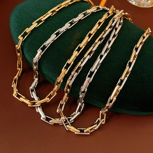 Close-up of gold and silver chain link necklaces displayed on green velvet padding