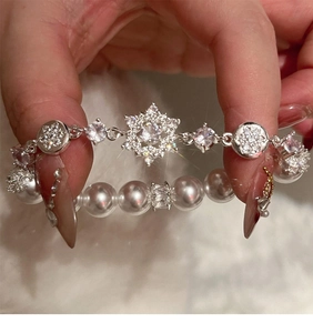 Close-up of double-layer silver snowflake bracelet with zircon accents and white pearls