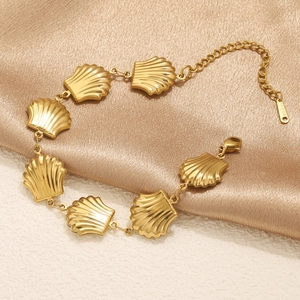 Golden shell-shaped pendant bracelet in stainless steel on a champagne silk background