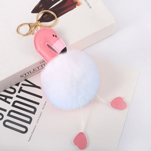 Detail of flamingo keychain with white faux fur pompom and pink leather on magazine