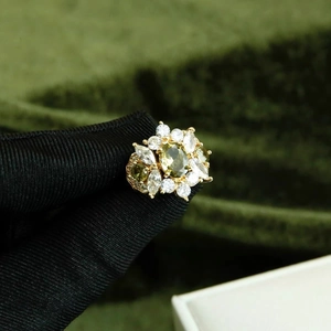 Detail view of 14k gold plated flower ring with olive green stone and white crystals