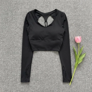 Detail of black slim fit yoga top featuring back cutout, thumb holes, and built-in bra pads