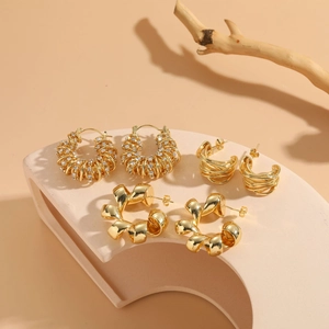 Macro shot of 14K gold plated twisted earrings and pavé zircon hoops on a stone base