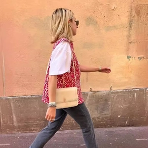 Outdoor street view of a woman wearing a red vintage double-sided print vest and white t-shirt