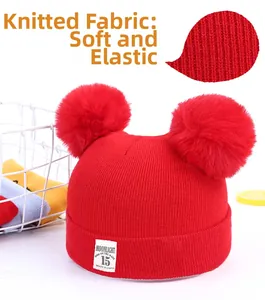 Detail of red knit baby hat with double pom poms and moonlight woven label
