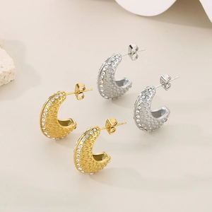 Détail de boucles d'oreilles en C avec finition texturée et zircons en or et argent
