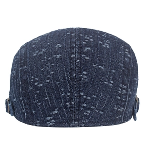 Detail of dark blue denim flat cap with spot texture and vintage copper side buckle