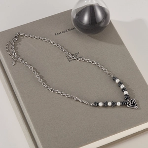 Detailed view of titanium steel necklace with white pearls and hollow heart pendant