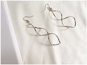 Detailed macro view of silver minimalist spiral wave drop earrings with polished finish