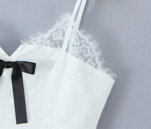 Detail of white eyelet embroidery on camisole with lace trim and black satin bow