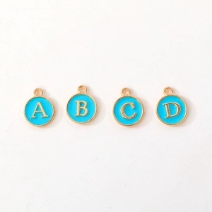 Detailed view of four golden alloy round letter pendants with blue enamel for DIY jewelry