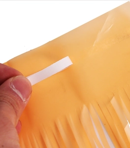 Detail of yellow macaron tinsel fringe curtain showing the adhesive strip for party decoration