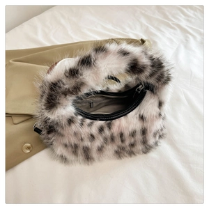 Detail shot of plush black and white spotted crescent handbag with top zipper closure