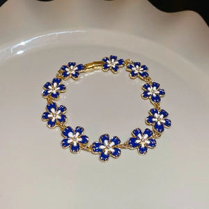 Detail of vintage gold bracelet with blue and white enamel flowers and crystals