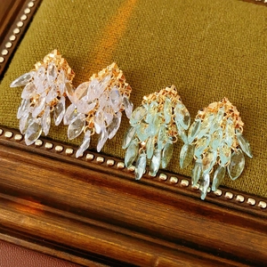 Détail des boucles d'oreilles à pompons géométriques avec cristaux bleus sur velours