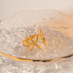 Detailed close-up of 18k gold-plated starfish and seashell motif on an open ring