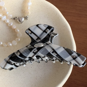 Classic black and white checkered hair claw clip with a refined gold oval metal logo tag