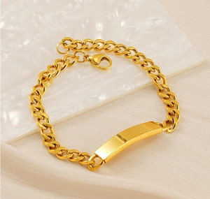 Dettaglio del bracciale a catena cubana dorata con placca rettangolare su sfondo di seta