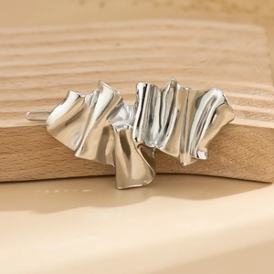 Detailed close-up of a silver liquid metal hair clip with abstract folded texture