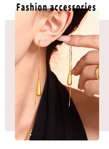 Close-up of elegant gold water drop tassel earrings worn by a model in soft lighting