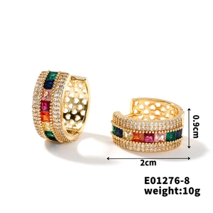 Macro detail of gold hoop earrings with colorful square gems and white zircon accents