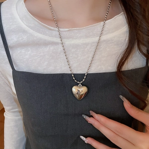 Close-up of minimalist silver heart pendant necklace on model with bead chain detail