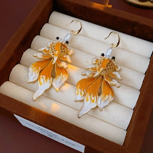 Macro view of vintage goldfish earrings with orange enamel details and pearl accents