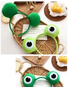 Gros plan de serre-têtes en peluche grenouille verte avec de grands yeux de dessin animé