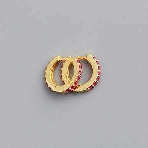 Macro shot of S925 sterling silver stamp on gold hoops with inlaid red cubic zirconia