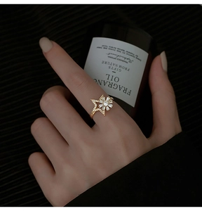 Close-up of a golden windmill star ring with white zircons on a model's finger