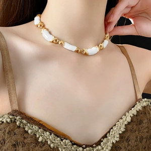 Detail of vintage enamel bamboo link necklace in gold and white on a female model