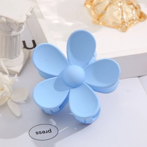 Detailed close-up of a matte sky blue five-petal flower hair claw clip on a white tray