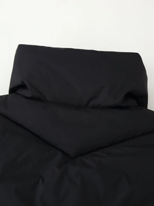 Detail of windproof stand-up collar on black quilted puffer jacket with zipper