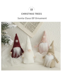 Detailed view of four felt Christmas elf gnomes on white lace with cedar branch decor