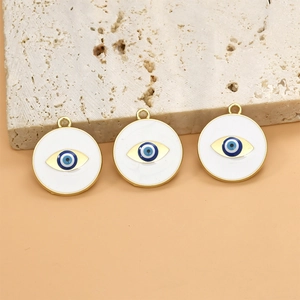 Detailed macro view of three gold evil eye pendants with white enamel on stone surface